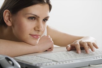 Woman leaning on table using computer keyboard.