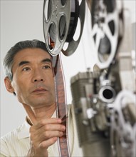 Asian man looking film in projector.