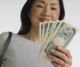 Low angle view of Asian woman holding Japanese money.