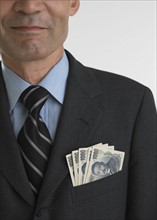 Close up of businessman with paper money in breast pocket .
