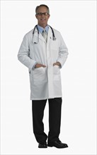 Studio shot of male doctor with hands in pockets.
