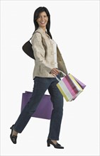 Studio shot of woman carrying shopping bags.