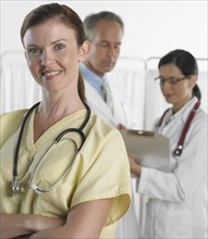 Female doctor smiling with doctors in background.