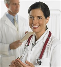 Female doctor smiling with doctor in background.