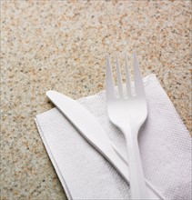 Close up of plastic knife and fork on napkin.