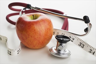 Close up of apple, tape measure and stethoscope.