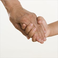 Close up of senior's hand holding child's hand.