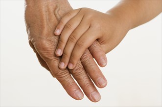 Close up of child holding adults hand.