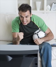Man holding soccer ball and watching television.