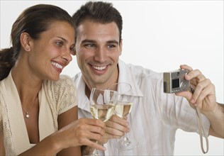 Couple talking own photograph while toasting with wine.