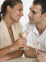 Couple smiling at each other and drinking wine.