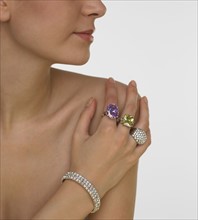Woman with bare shoulders putting jeweled hand on shoulder.