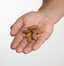 Close up studio shot of man holding almonds .