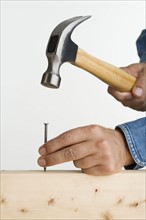 Close up of man using hammer and nail.