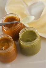 Close up of baby food in jars with spoon and bib.