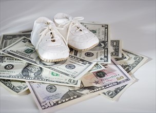 Baby shoes on stack of US Dollars.