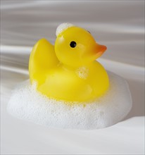 Close up of rubber duck toy with soap bubbles.
