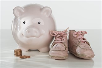 Studio shot of baby shoes and piggy bank.