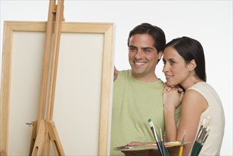 Couple smiling and looking at easel.
