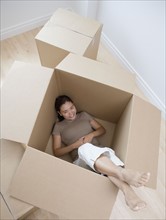 Woman sitting in empty moving box.