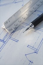 Close up of ruler and pen on blueprints.