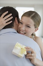 Woman holding gift and hugging husband.