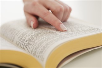 Woman's finger on page in Bible.