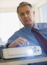 Senior businessman using projector in conference room.