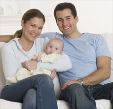 Portrait of family with baby on sofa.