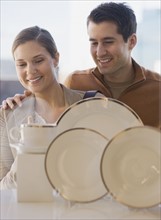 Couple looking at tableware in shop window.