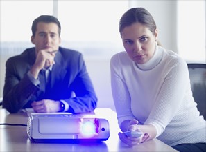 Businesspeople using projector in conference room.