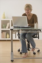 Senior woman with bare feet looking at laptop.