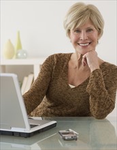 Portrait of senior woman next to laptop.