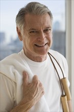 Portrait of senior man holding jump rope over shoulder.