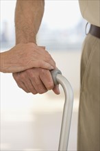 Senior couple's hands on cane.