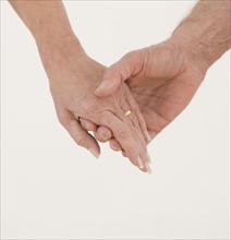 Close up of senior couple holding hands.