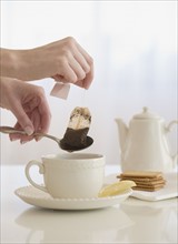 Woman taking tea bag out of cup.