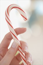 Close up of woman holding candy cane.