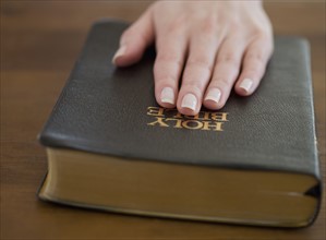 Woman's hand on Bible.