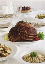 Spiral ham and side dishes on set table.