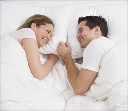 Couple smiling at each other in bed.