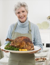 Portrait of senior woman holding Thanksgiving turkey.