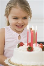 Girl smiling at birthday cake.