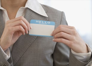 Businesswoman putting on Hello My Name Is sticker.