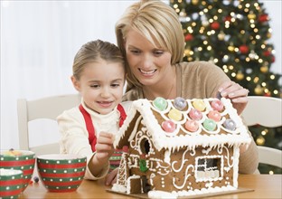 Mother and daughter making gingerbread house.