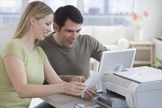 Couple printing picture with laptop.