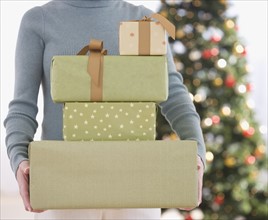 Woman holding stack of Christmas gifts.