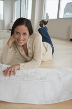 Woman laying on floor with blueprints.