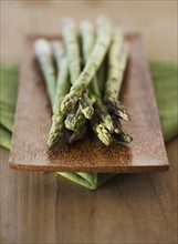 Close up of asparagus on wooden plate.