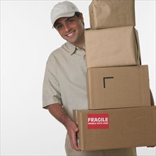 Studio shot of deliveryman holding stack of boxes.